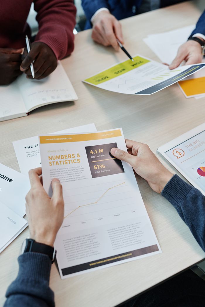 who-we-are A group reviews business statistics and reports on a wooden table.